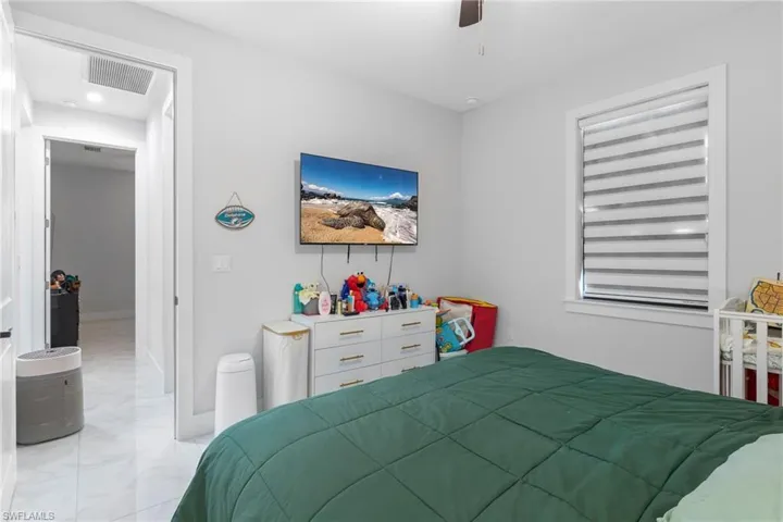 Bedroom featuring light marble finish floors and a ceiling fan