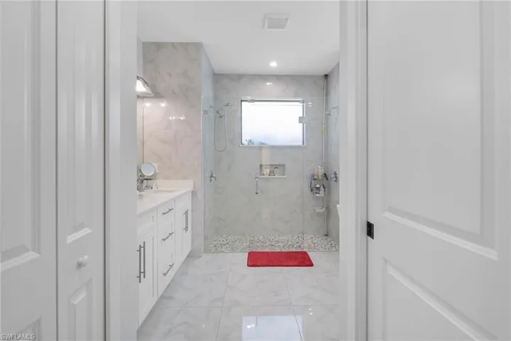 Full bathroom with vanity, a marble finish shower, and light marble finish floors