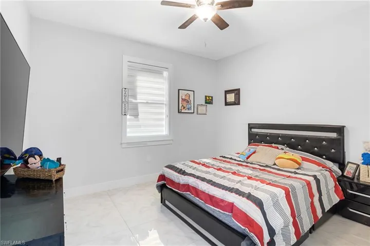 Bedroom with ceiling fan and light marble finish floors