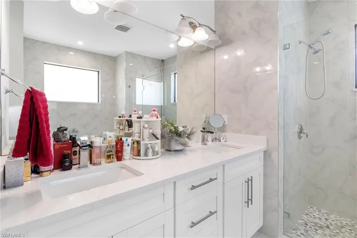 Full bathroom with tile walls, a marble finish shower, and double vanity