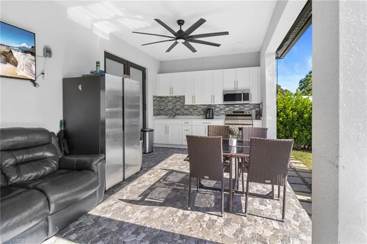 Kitchen with light countertops, white cabinetry, appliances with stainless steel finishes, decorative backsplash, and a ceiling fan
