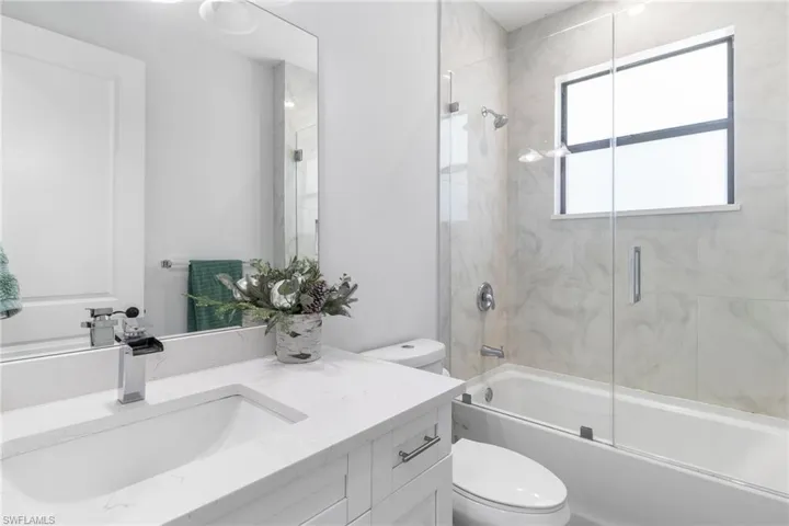 Full bath featuring vanity and shower / bath combination with glass door