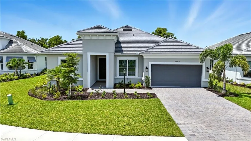 View of front of home featuring a garage, decorative driveway, a front yard, stucco siding, and a tiled roof
