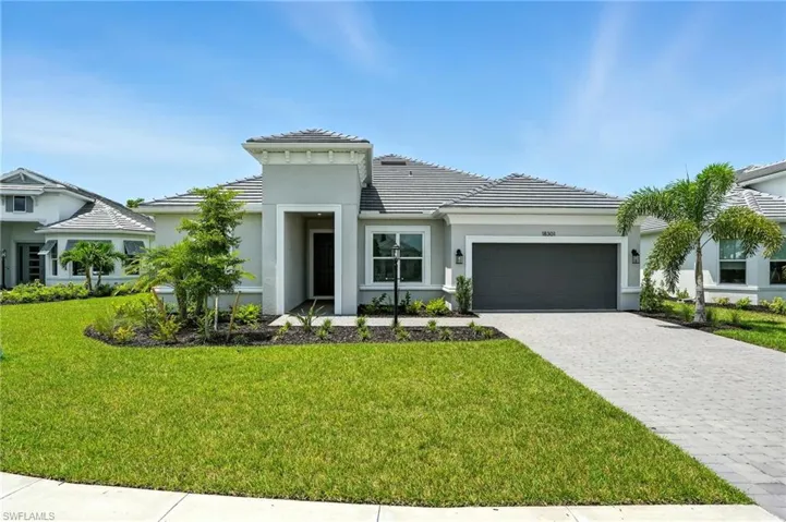 Prairie-style house featuring a garage, a tiled roof, decorative driveway, and a front lawn