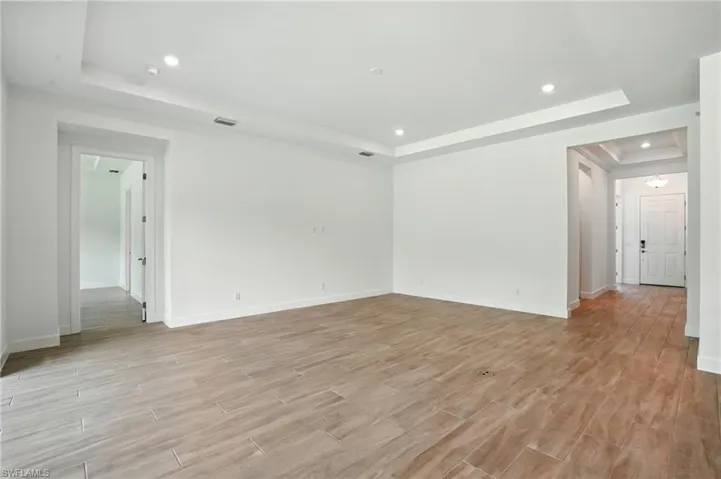 Unfurnished living room with a raised ceiling, recessed lighting, and light wood finished floors