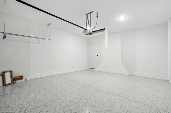 Garage featuring baseboards and a garage door opener
