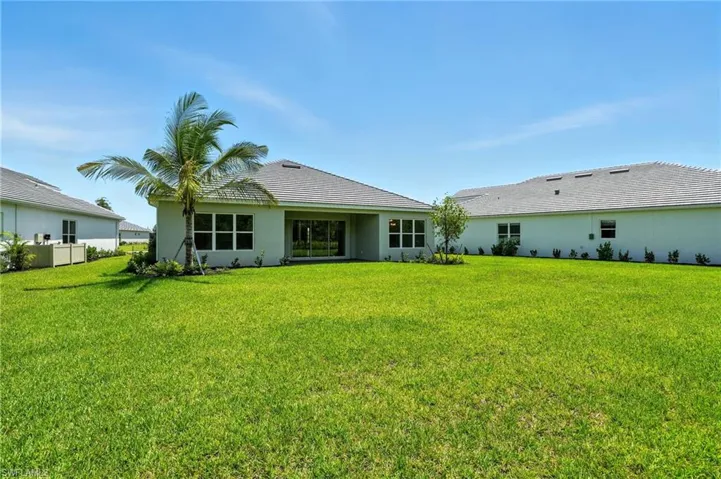 Back of house featuring a yard and stucco siding