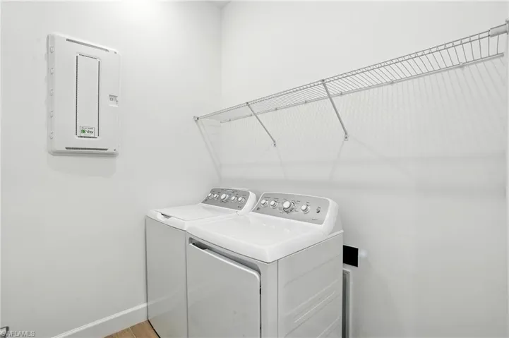 Washroom with washing machine and clothes dryer and baseboards