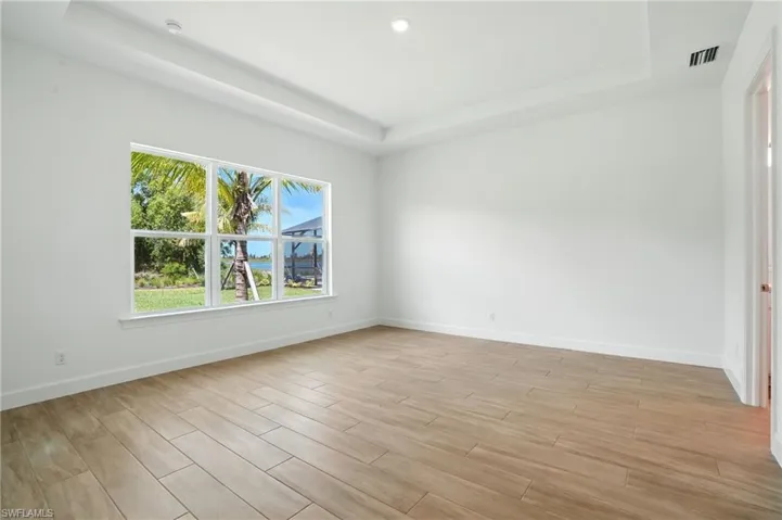 Unfurnished room featuring a tray ceiling, light wood-type flooring, and recessed lighting