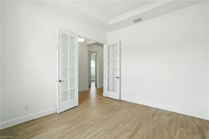 Unfurnished room with french doors and light wood-type flooring