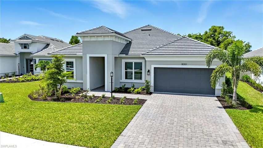 View of front of home with a front lawn, a garage, decorative driveway, and a tile roof