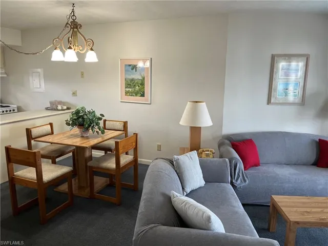 Dining room with dark carpet and an inviting chandelier