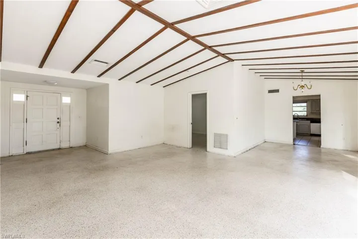 Unfurnished living room featuring lofted ceiling with beams, an inviting chandelier, and sink