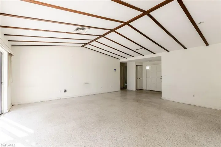 Empty room featuring vaulted ceiling