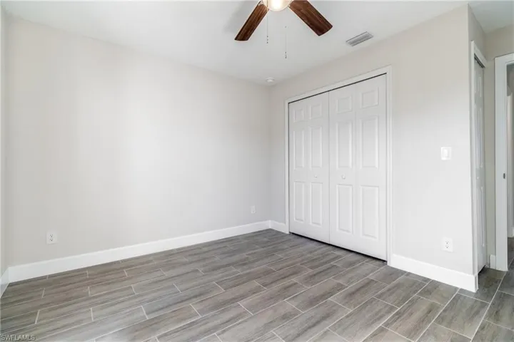 Unfurnished bedroom with ceiling fan and a closet