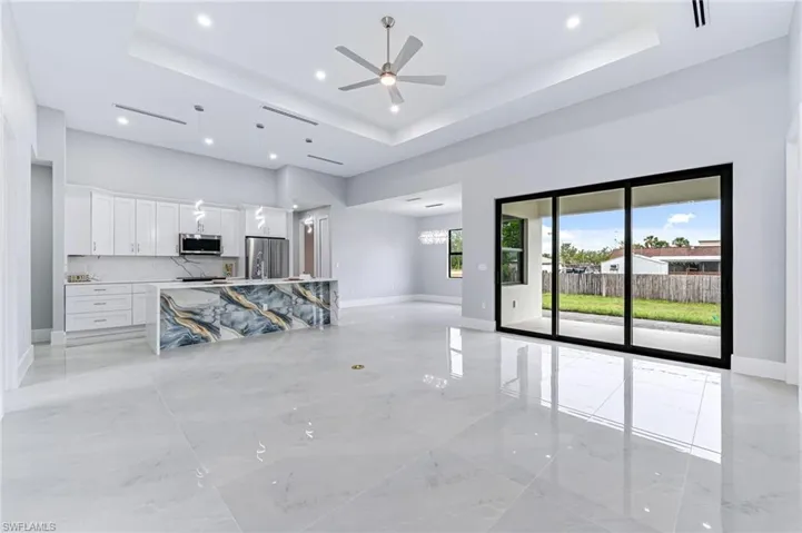 Unfurnished living room with ceiling fan, a high ceiling, and a tray ceiling