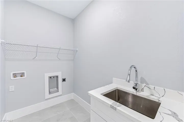Laundry area with cabinets, sink, washer hookup, and hookup for an electric dryer