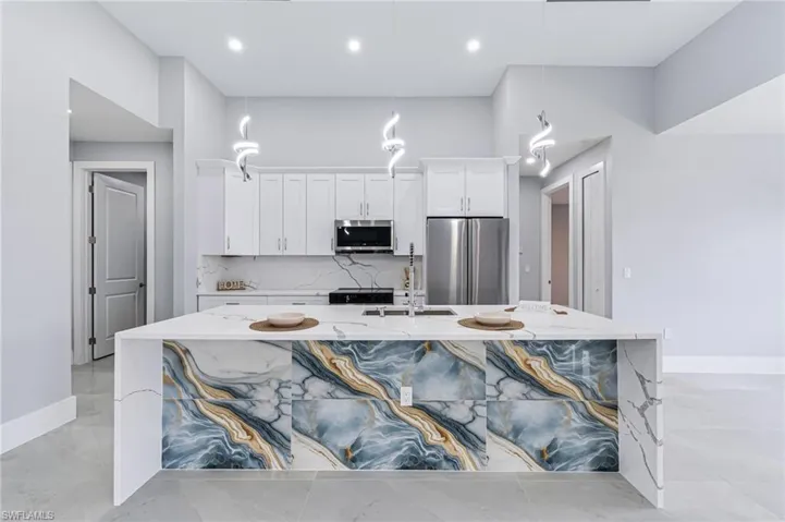 Kitchen featuring white cabinets, sink, light stone countertops, appliances with stainless steel finishes, and tasteful backsplash