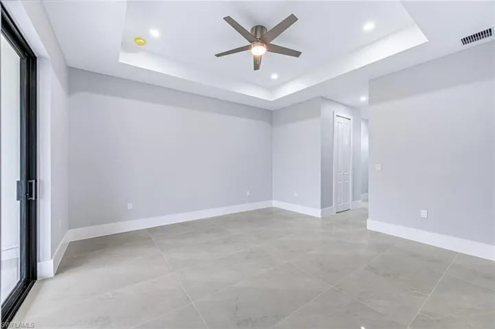 Empty room with ceiling fan and a raised ceiling