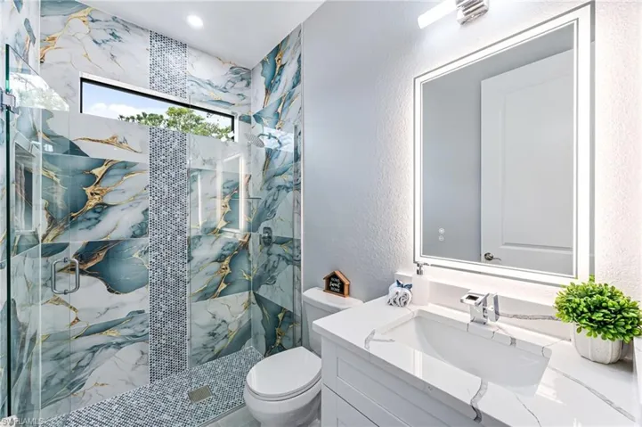 Bathroom with vanity, toilet, and a shower with shower door