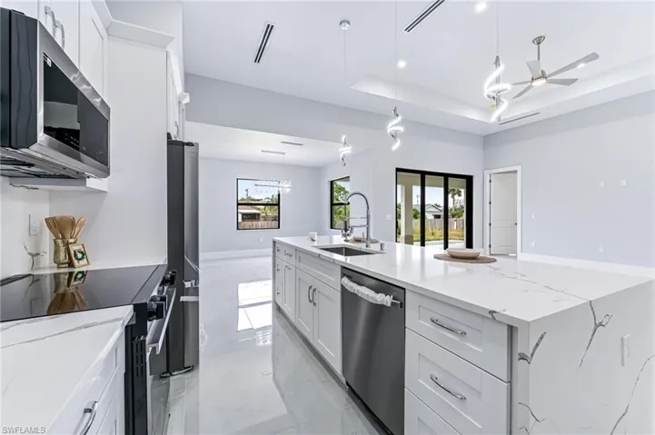 Kitchen featuring white cabinets, ceiling fan, sink, and stainless steel appliances