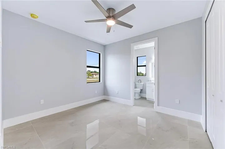 Unfurnished bedroom featuring ceiling fan, a closet, and ensuite bath