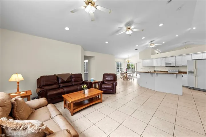 Living area with ceiling fan, light tile patterned floors, lofted ceiling, and recessed lighting