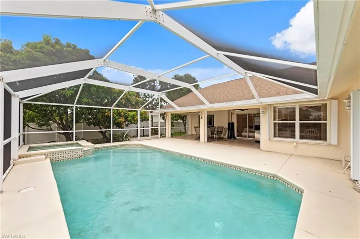 View of swimming pool with a patio, ceiling fan, a fenced backyard, a pool with connected hot tub, and glass enclosure