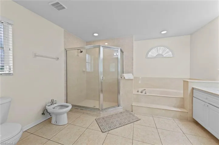 Bathroom featuring a garden tub, a stall shower, a bidet, vanity, and tile patterned flooring