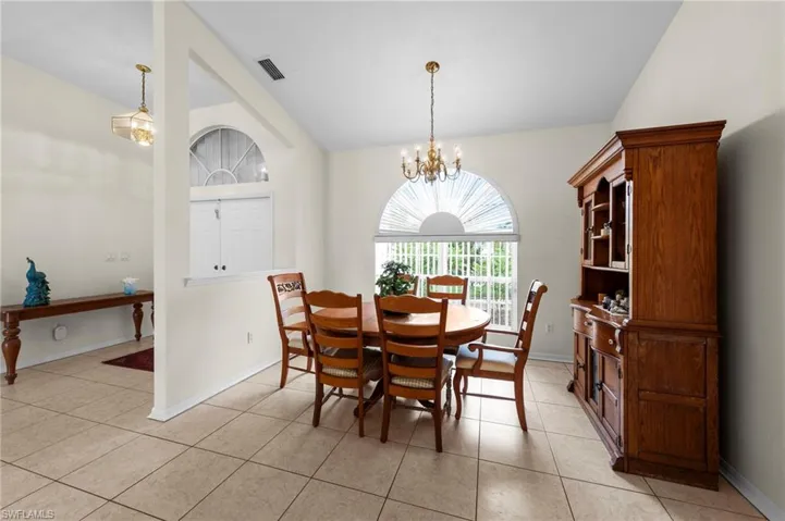Dining area featuring a chandelier, light tile patterned floors, and lofted ceiling