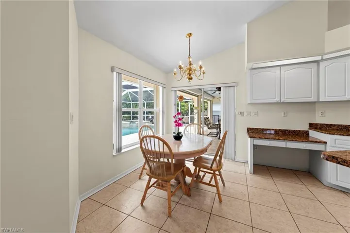 Dining area with vaulted ceiling, a chandelier, light tile patterned floors, and an office area