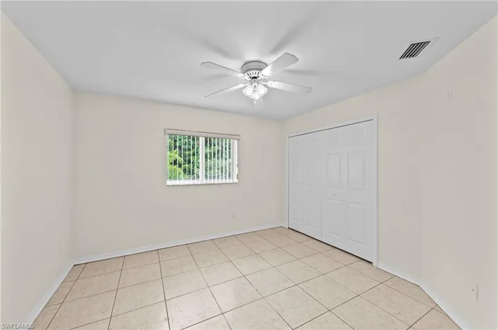 Unfurnished bedroom with a closet, light tile patterned floors, and a ceiling fan