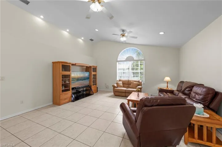 Living room featuring ceiling fan, vaulted ceiling, light tile patterned flooring, and recessed lighting