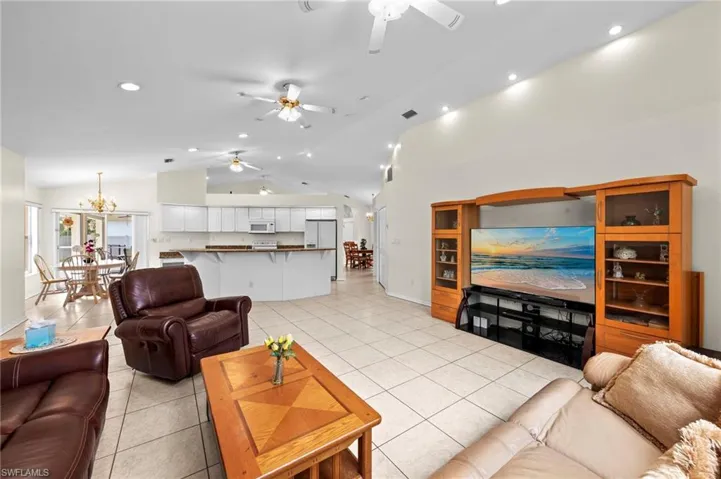 Living room with a ceiling fan, lofted ceiling, light tile patterned floors, recessed lighting
