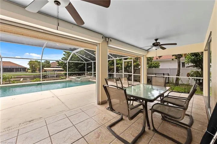 View of swimming pool featuring a ceiling fan, a patio, a pool with connected hot tub, and outdoor dining area