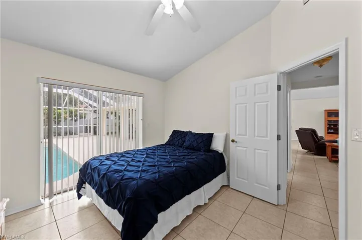 Bedroom with lofted ceiling, light tile patterned floors, a ceiling fan, and access to exterior