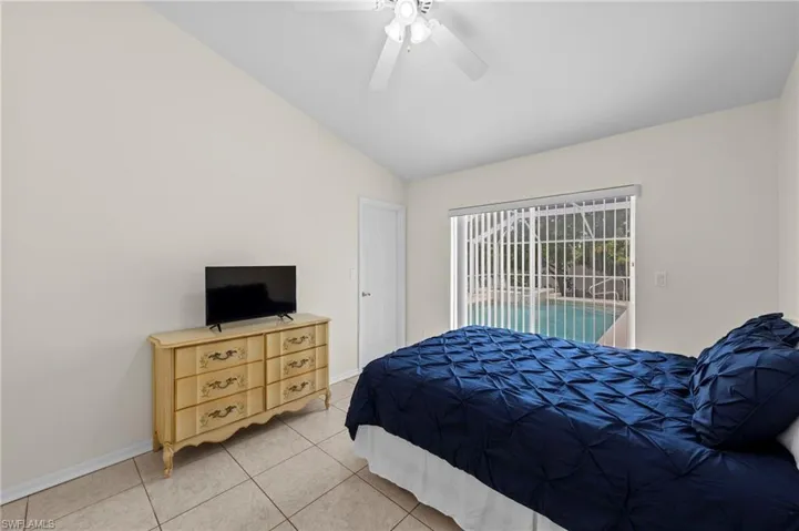 Bedroom with lofted ceiling, light tile patterned flooring, access to exterior, and ceiling fan