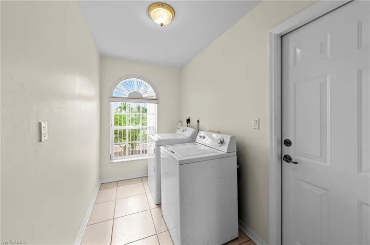 Laundry area with separate washer and dryer and light tile patterned floors