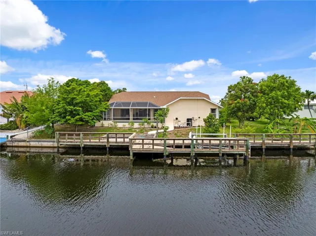 Dock area with a water view, a lanai, and a lawn