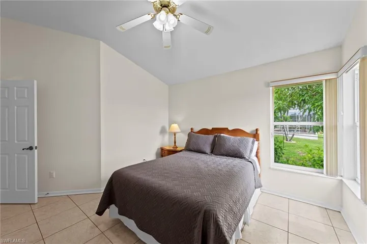 Bedroom with light tile patterned floors, ceiling fan, and vaulted ceiling