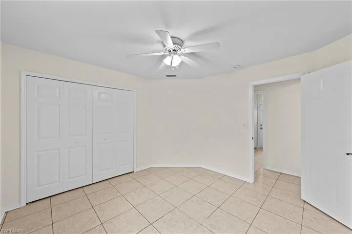 Unfurnished bedroom with light tile patterned floors, a closet, and ceiling fan