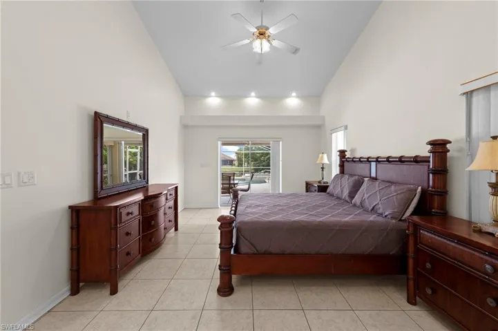Bedroom with high vaulted ceiling, access to exterior, light tile patterned floors, and a ceiling fan