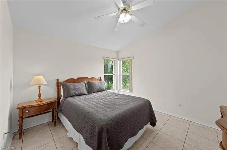 Bedroom with light tile patterned floors, vaulted ceiling, and a ceiling fan