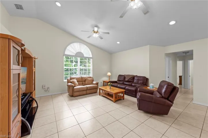Living area featuring vaulted ceiling, a ceiling fan, light tile patterned flooring, and recessed lighting