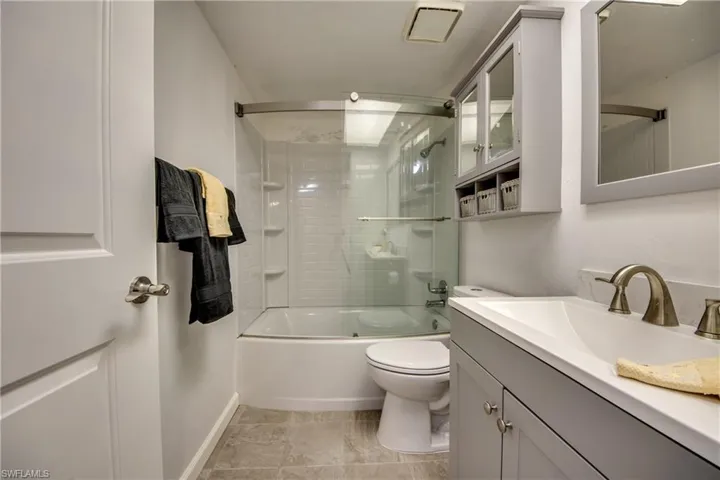 New glass enclosed tub, vanity and toilet.