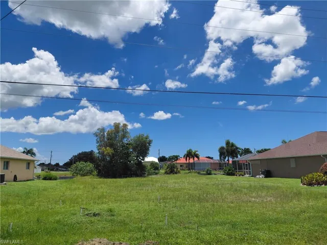 Expansive undeveloped lot featuring grassy terrain and surrounding residences