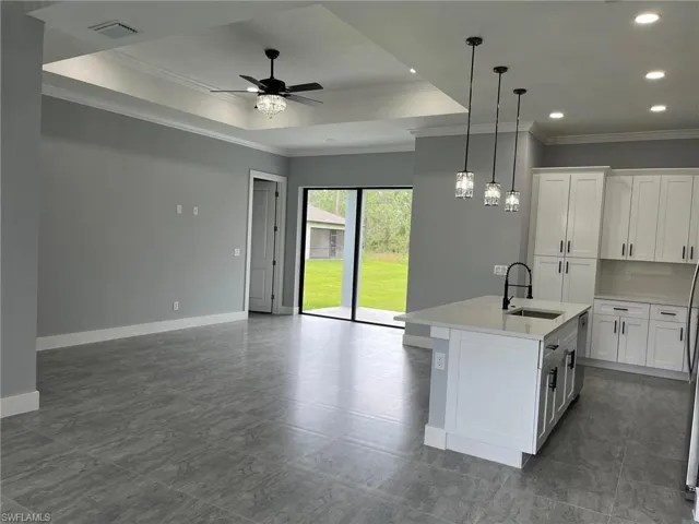Kitchen with white cabinets, crown molding, sink, and an island with sink