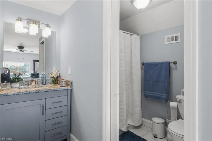 Full bath featuring curtained shower, vanity, a ceiling fan, and marble finish flooring