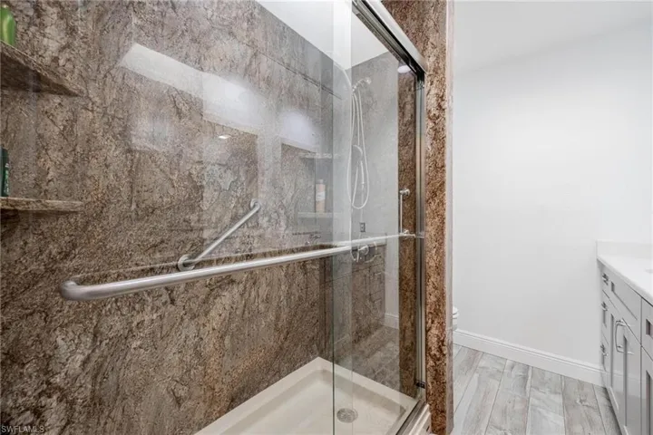Bathroom with a shower with door, toilet, vanity, and wood-type flooring