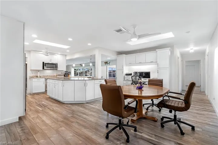 Dining space featuring ceiling fan, a skylight, and light hardwood / wood-style flooring